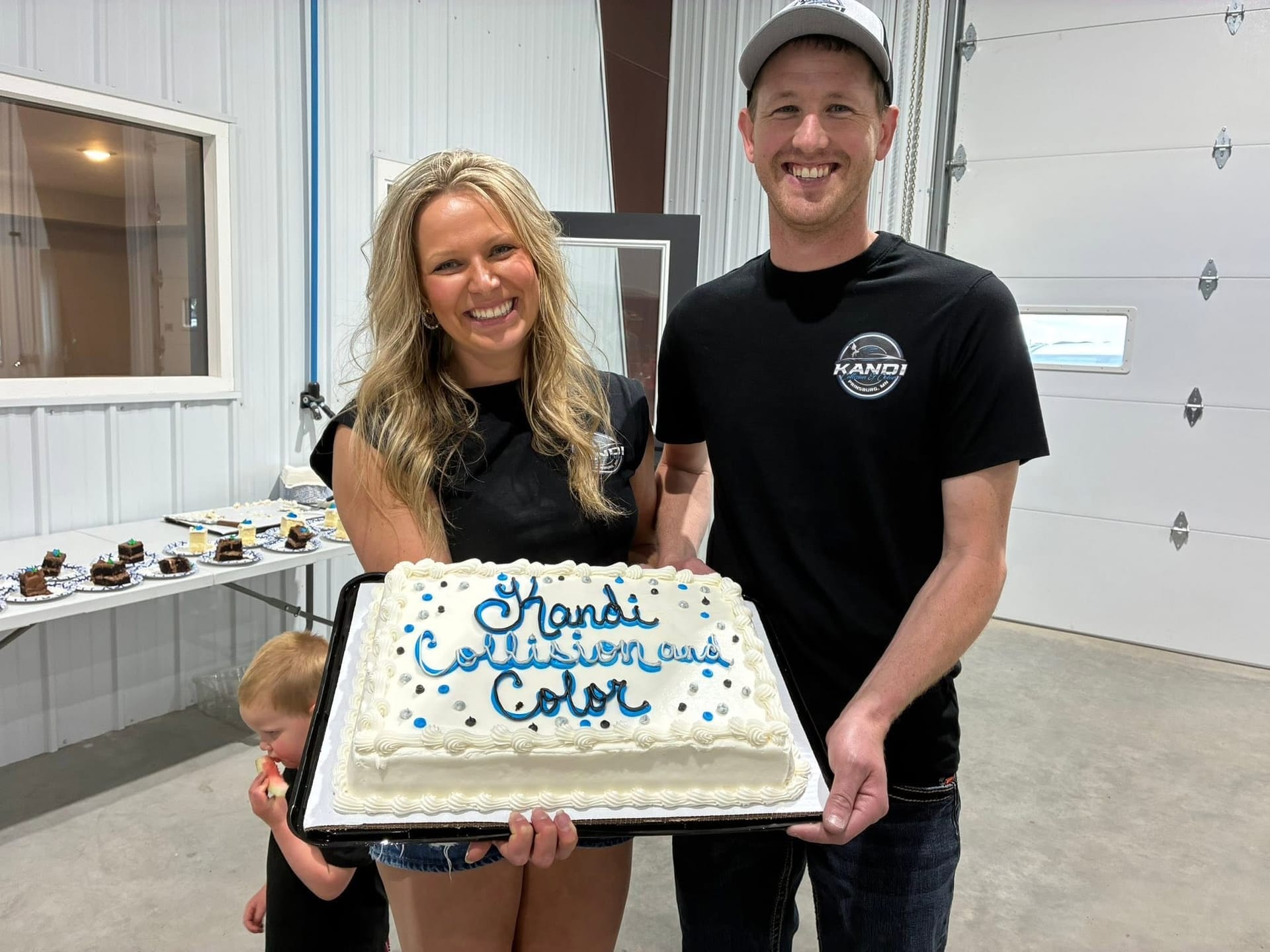 The owners of Kandi Collision & Color holding a celebration cake at the shop's opening