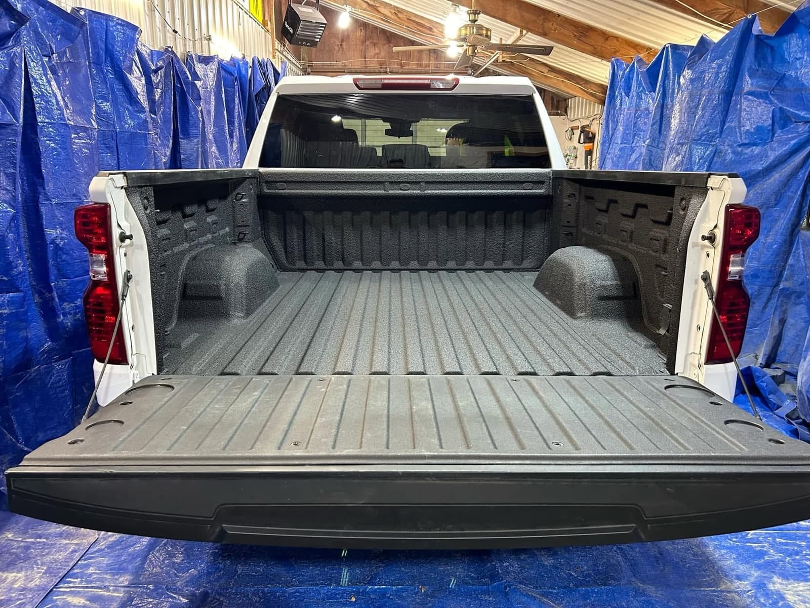 White Chevrolet Silverado with a freshly sprayed black bed liner and the tailgate down