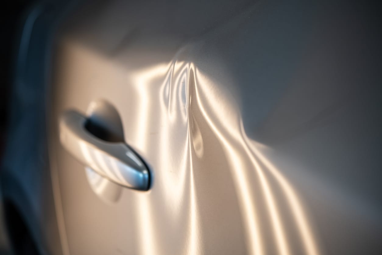 Raking light across a deep dent in a silver car door