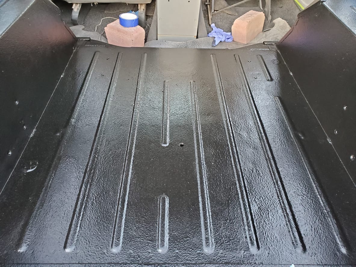 Freshly sprayed black textured bed liner coating a pickup bed floor