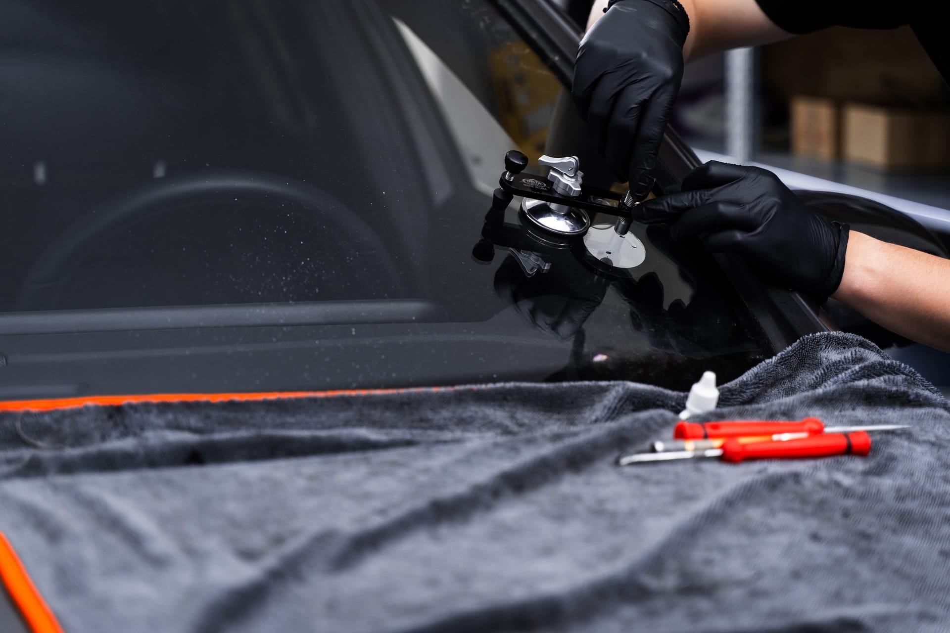 Windshield repair tool bonded to glass while resin is injected into a chip