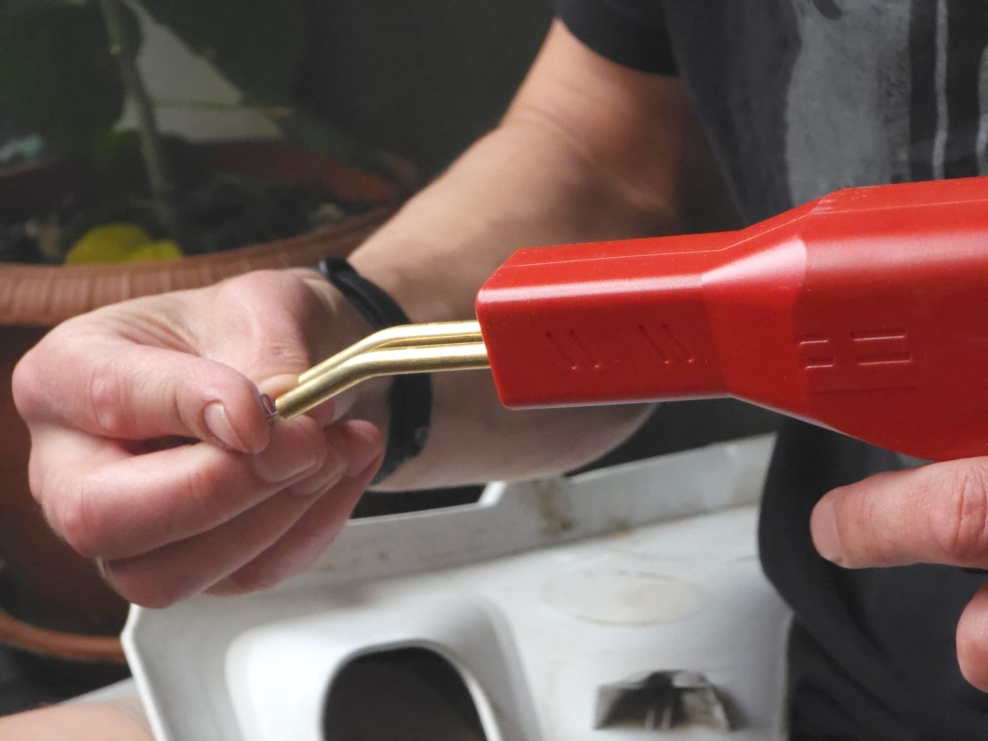 Hands using a hot plastic welding tool to repair a cracked bumper cover